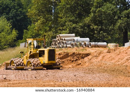 An earth breaking machine and pipes on a dirt construction project