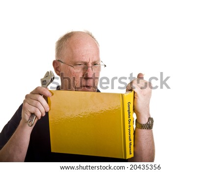 An older man looking at a repair book holding a wrench and looking confused