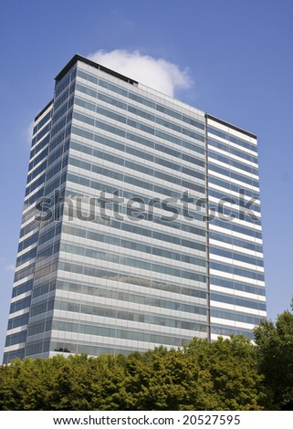 A blue and white office tower rising from the trees
