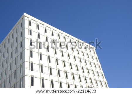 A office building of white concrete cubes and glass against a blue sky