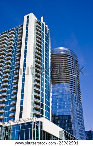 A condo tower with many balconies and a blue office tower against a blue sky