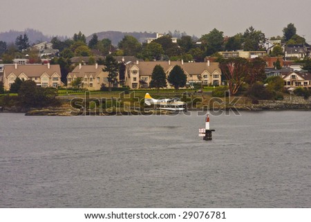 A sea plane cruising in to land by houses on the land
