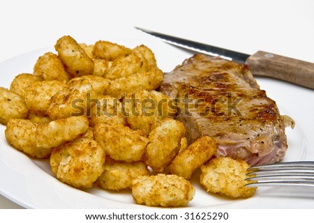 Steak and potato puffs on a white plate