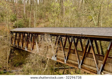 An old covered wood bridge spanning a gorge in the forest