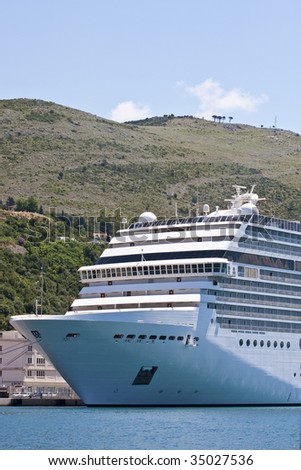 The bow of a luxury cruise ship on the shore of hilly croatia