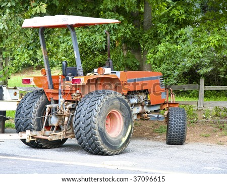 An old orange tractor on the edge of a road