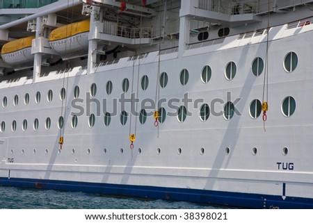 Side of a luxury cruise ship with yellow pulleys for lifeboats