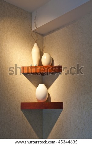 Decorative pots on a well lit shelf in the corner of a room