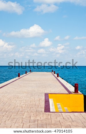 A straight pier into a blue sea with orange steps on the side