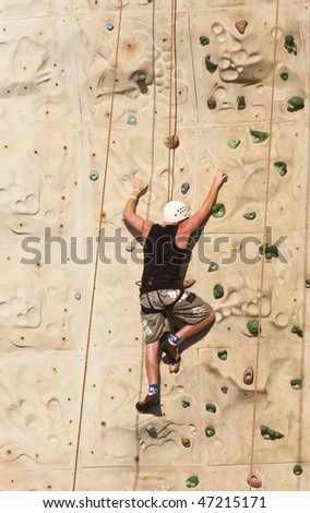 A man climbing a rock wall using ropes and harness