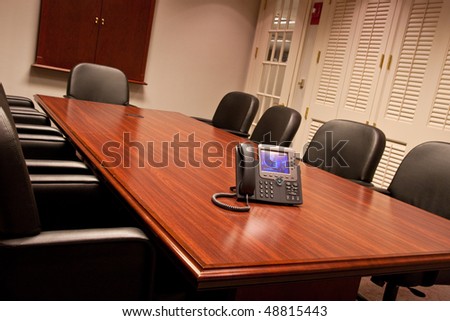 A large conference room table shot from a low angle with a business phone on the end