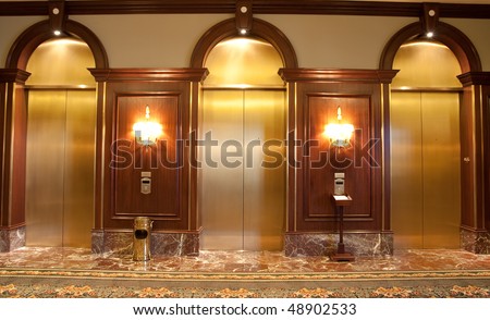 Three elevators in a nice wood and brass lobby