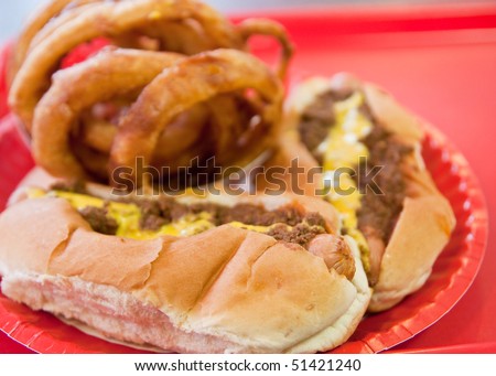 Two chili dogs and an order of onion rings on a red tray
