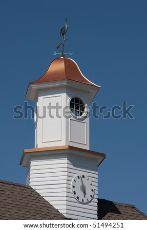A traditional clock tower with a copper roof and wind vane