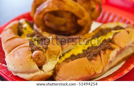 Two chili dogs with mustard and onion rings