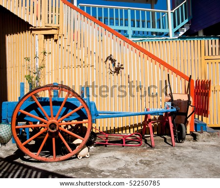 An old wagon in front of a colorful fence
