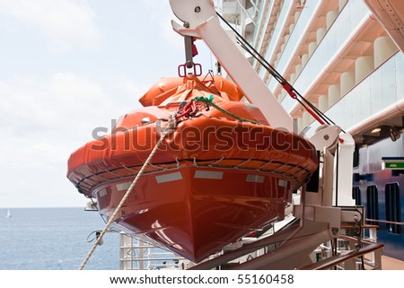 An orange lifeboat in its harness on the side of a cruise ship