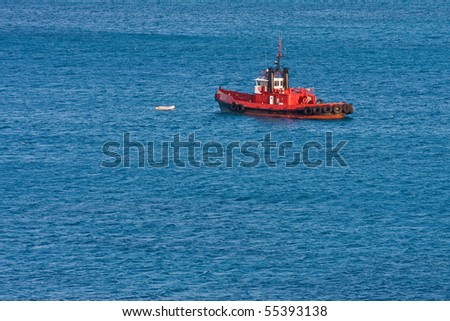 A bright orange pilot boat pulling a skiff on blue water