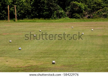 A soccer field with many balls scattered around