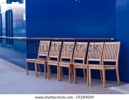 Four wooden chairs by blue wall on a ships deck