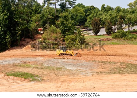 A yellow bulldozer working a dirt field on a construction site