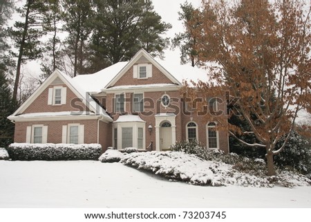 A snow covered brick house and front yard