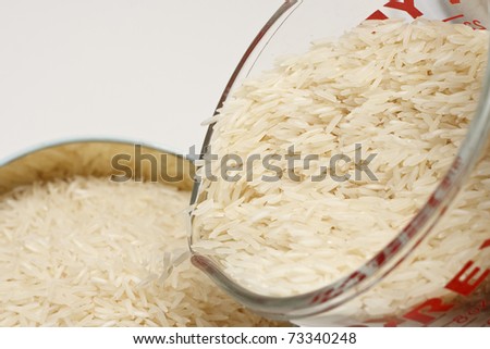 White Rice Pouring from Glass Measuring Cup Into Canister