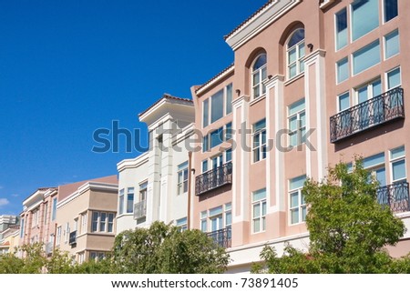 Pink and White stucco buildings with black iron railings over windows