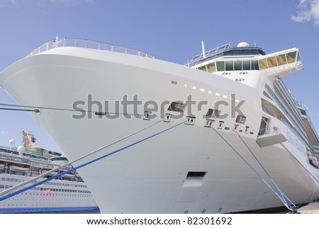 A huge luxury cruise ship tied to a pier with blue and white ropes