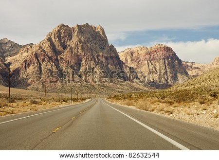 A wide empty road in the desert toward distant mountains