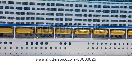 Side of a Luxury Cruise Ship with Balconies and Yellow Lifeboats