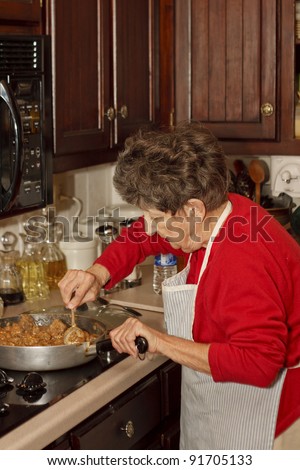 An older woman working at a stove in a traditional kitchen