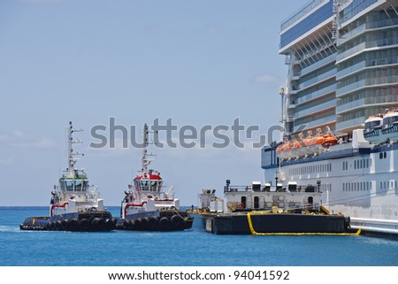 Two tugboats and a barge tied up to a cruise ship