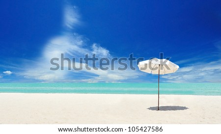 White umbrella on the beach with cloudy blue sky in background