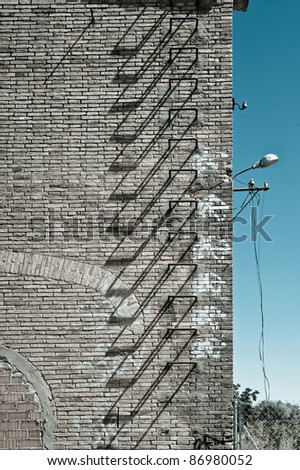 part of a facade of an abandoned factory with iron stairs for emergency