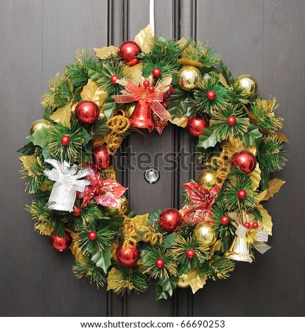 christmas wreath on dark wooden door with peephole in the center