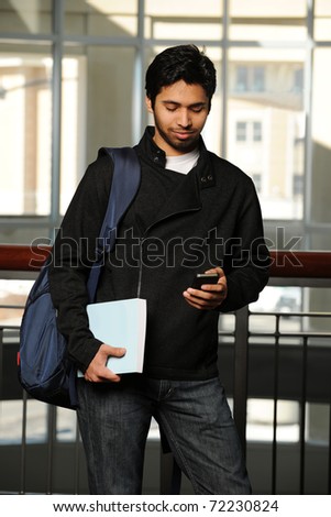 Young Eastern student with cell phone inside a College Building