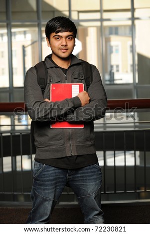 Young Eastern student holding a copybook inside a College building