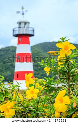 Lighthouse With Colorful Flowerbeds And Blue Sky