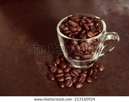 Coffee crop beans in little glass cup, vintage color background