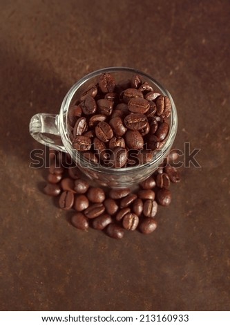 Coffee crop beans in little glass cup, vintage color background
