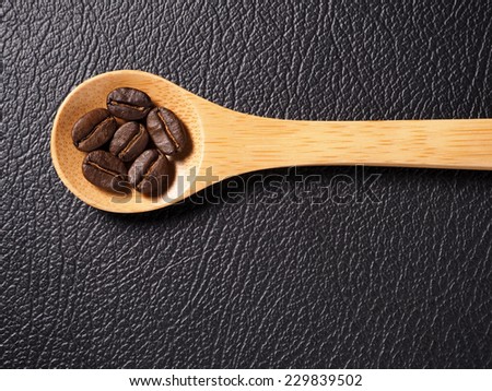 Coffee crop beans on bamboo spoon and leather texture background
