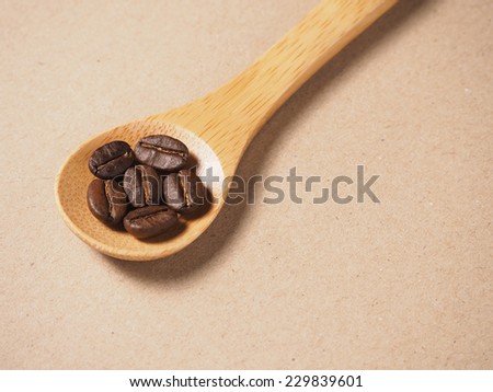 Coffee crop beans on  bamboo spoon and paper texture background