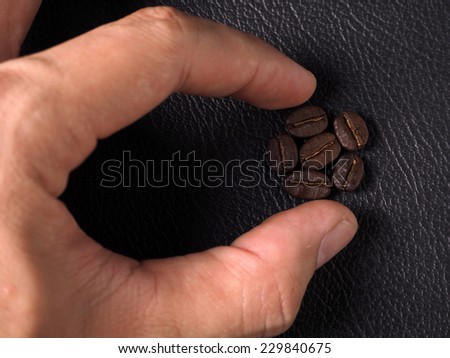 Coffee crop beans and hand on leather texture background