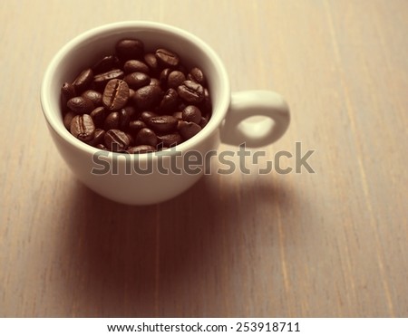 Coffee crop beans in white espresso cup, vintage color