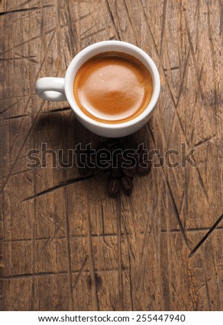 Cup of hot espresso coffee and coffee crop on wood board