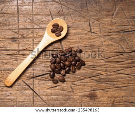 Coffee crop beans on bamboo spoon and wooden background