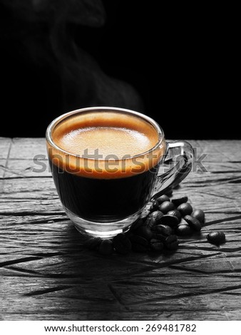 Cup of hot espresso coffee and coffee crop on wood board