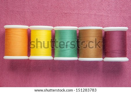 colourful cotton reel on cotton textile background