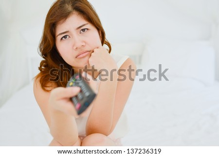 A young bored woman watching tv with remote